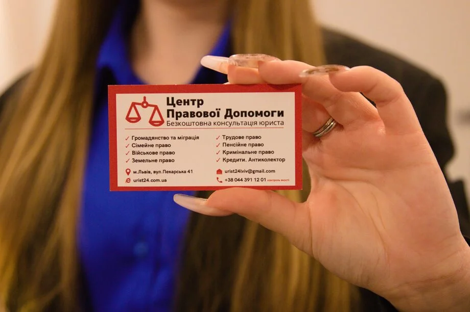 Дівчина-юрист тримає візитку Центру Правової Допомоги у Львові на Пекарській